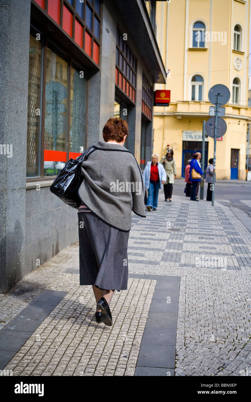 Donna che cammina lungo la strada nel centro della città di Praga Repubblica Ceca Foto Stock