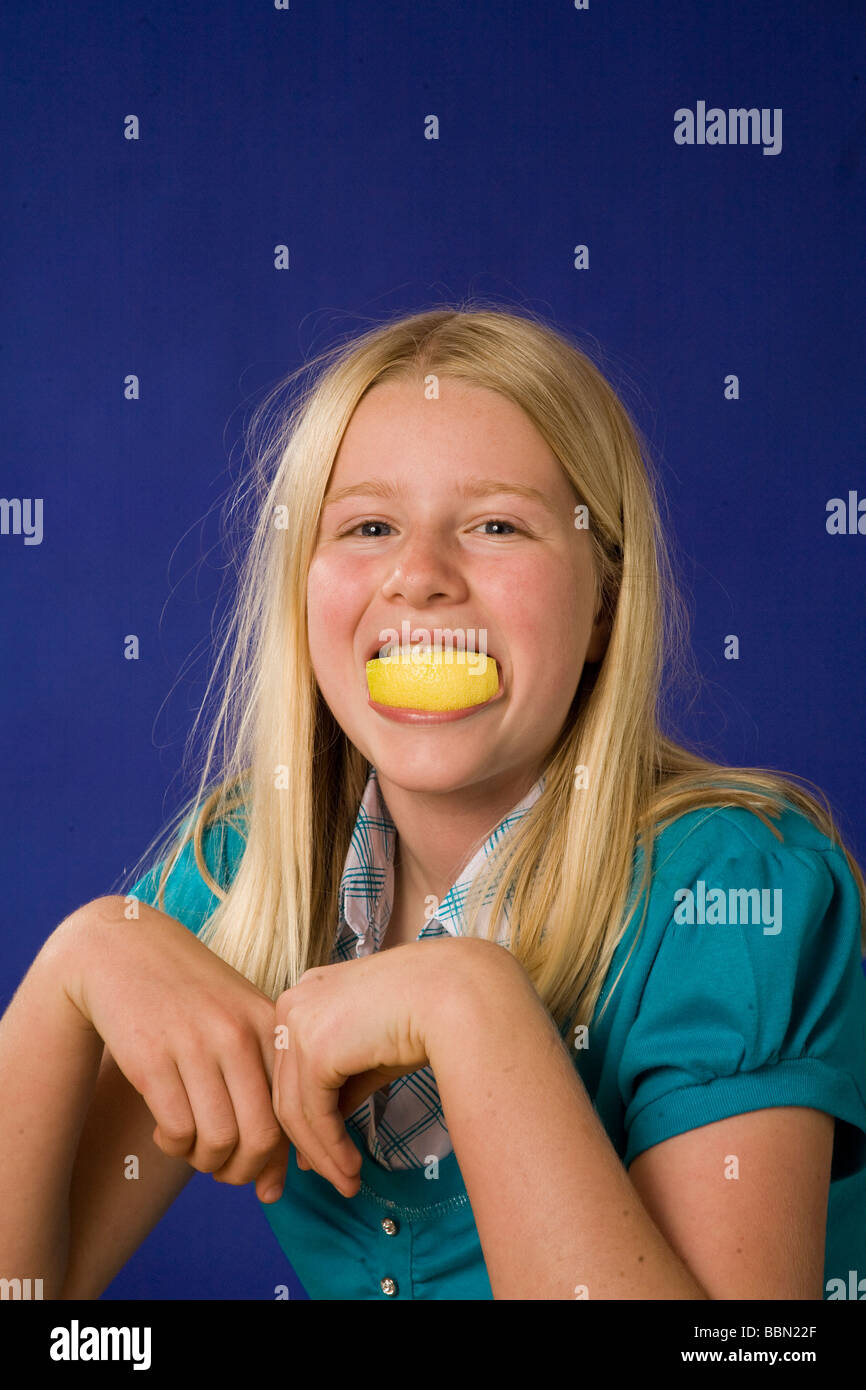 Ritratto di stupida ragazza 10-12 anno vecchia azienda sour limone i denti in bocca, studio shot tagliare fuori il signor ©Myrleen Pearson Foto Stock
