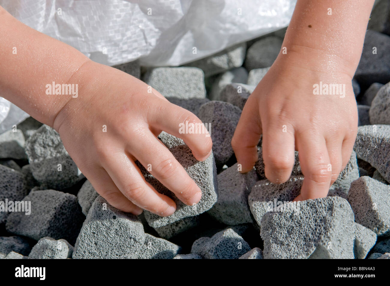 I bambini con le mani in mano afferrare in schiuma di vetro granulato, moderno materiale isolante dai rifiuti di vetro per isolamento del pavimento Foto Stock