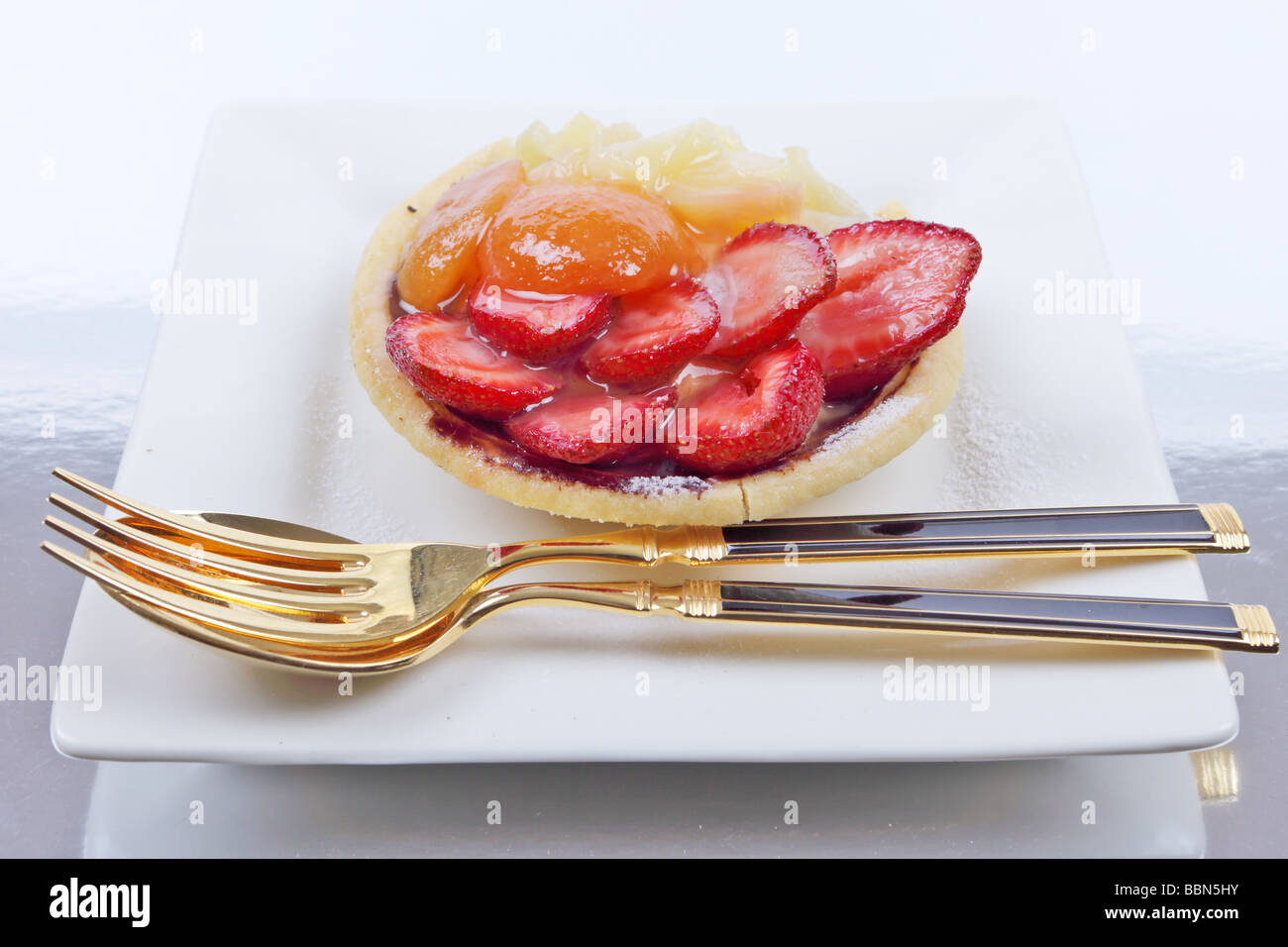 Flan di frutta con fragole e albicocche su un sfondo riflettente Foto Stock