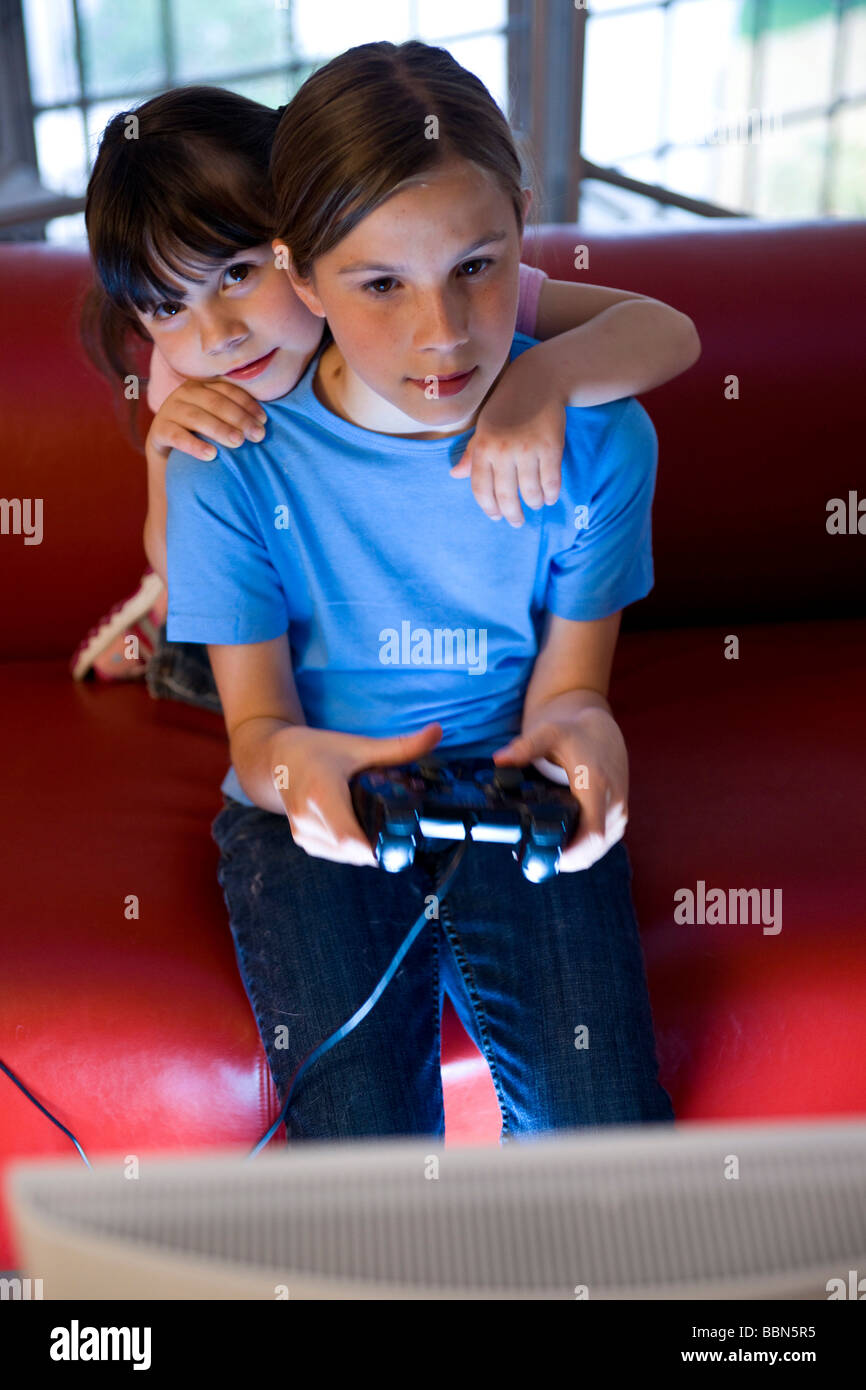 Una scolaretta e una ragazza kindergarten intensamente la riproduzione di un video gioco Foto Stock