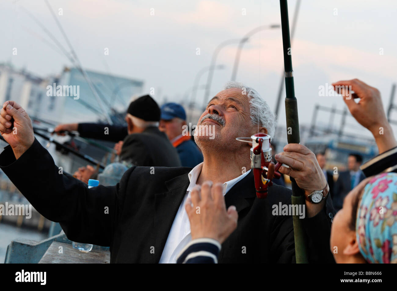 Capelli bianchi pescatore turco esamina la sua cattura, il Ponte Galata, Eminoenue, Istanbul, Turchia Foto Stock