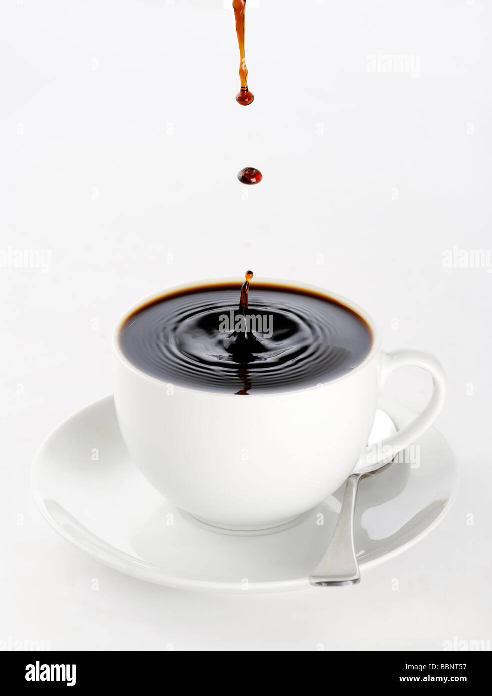 Una tazza di caffè nero pieno fino all'orlo con spruzzi di gocce sulla superficie che minacciano di spill over Foto Stock