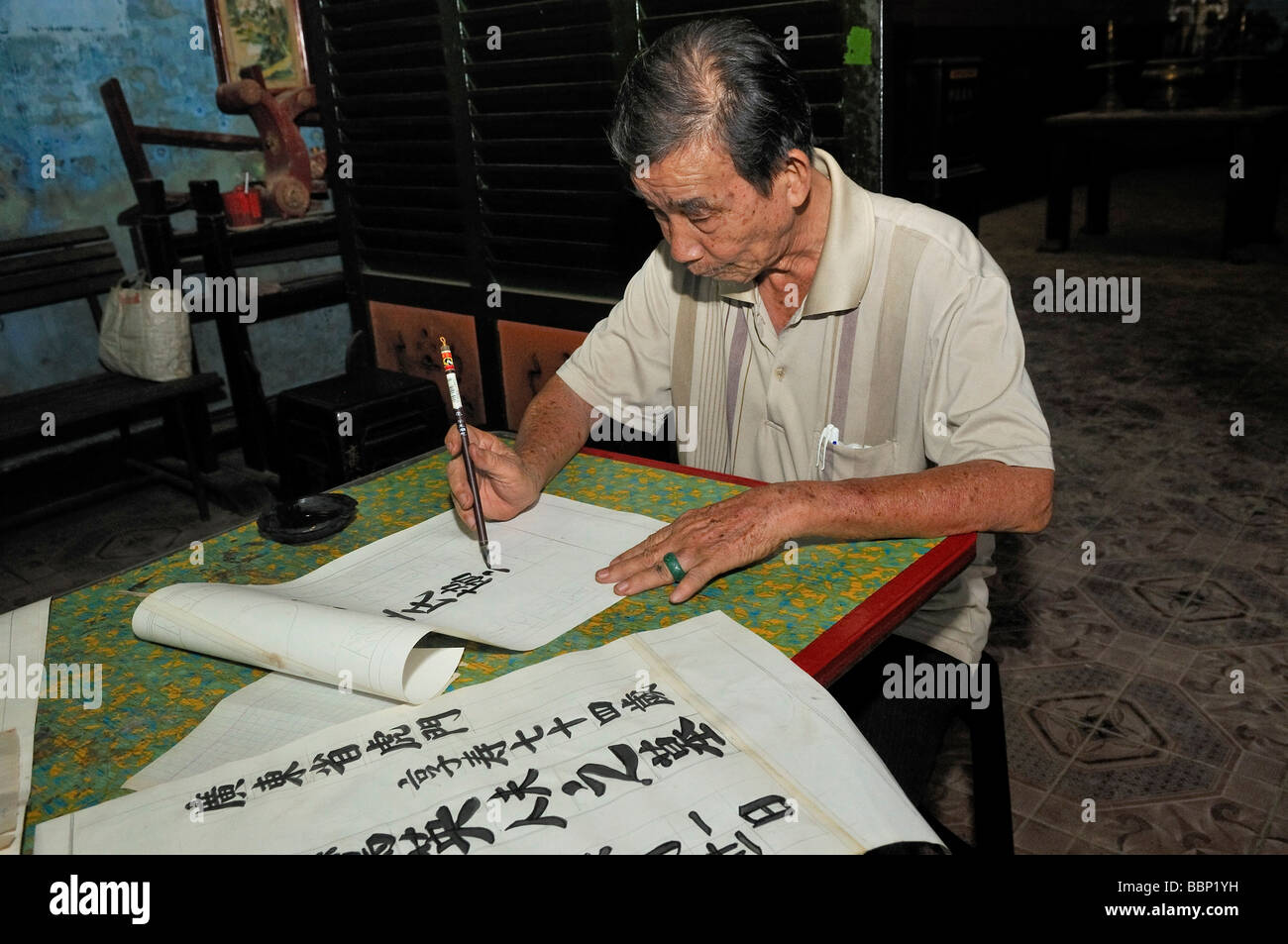 Il vecchio uomo, calligrapher al lavoro, seduti a un tavolo facendo una calligrafia, Vietnam, sud-est asiatico Foto Stock