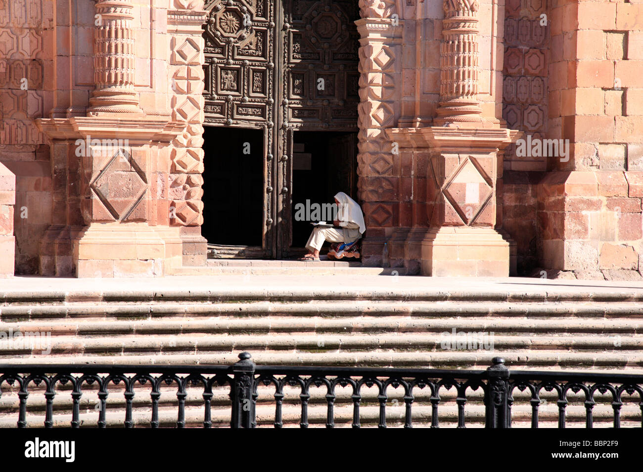 L'uomo situato di fronte alla porta della cattedrale di Zacatecas una piccola città in Messico edificio coloniale rosso barocca facciata in pietra Foto Stock