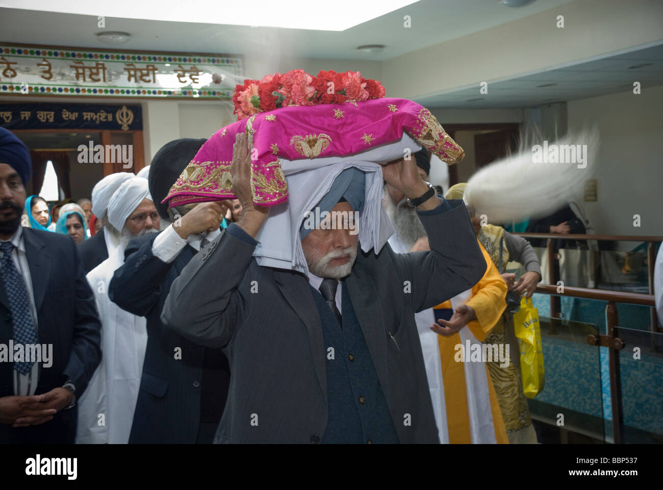 I sikh in Hounslow prendere parte in Vaisakhi celebrazioni e una processione. Un uomo porta il Guru Granth Sahib dal Gurdwara Foto Stock