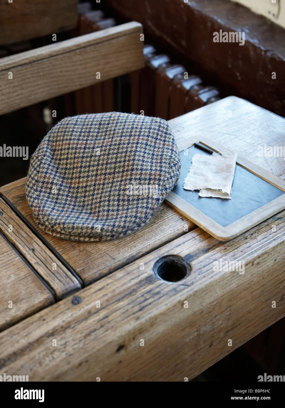 Cap e ardesia su un tradizionale banco di scuola, in una classe Foto Stock