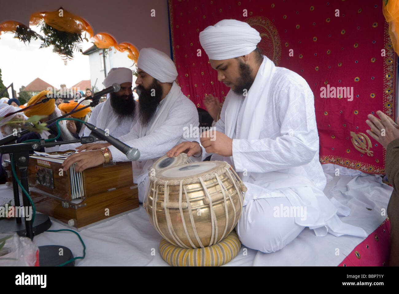 I sikh in Hounslow prendere parte in Vaisakhi celebrazioni e una processione - Musicisti sul galleggiante con il Guru Granth Sahib Foto Stock