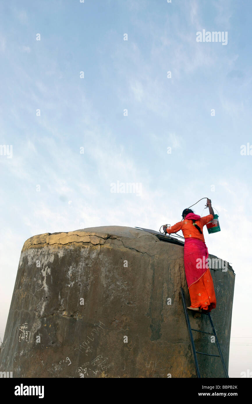 Una giovane donna tira l'acqua da un serbatoio in un villaggio rurale vicino a Jaisalmer in Rajasthan in India Foto Stock