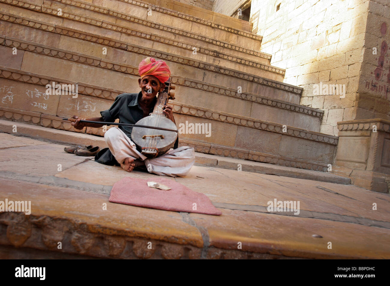 Un turbaned musicista di strada svolge un indiano tradizionale strumento a corda all'interno di Forte di Jaisalmer in Rajasthan in India Foto Stock
