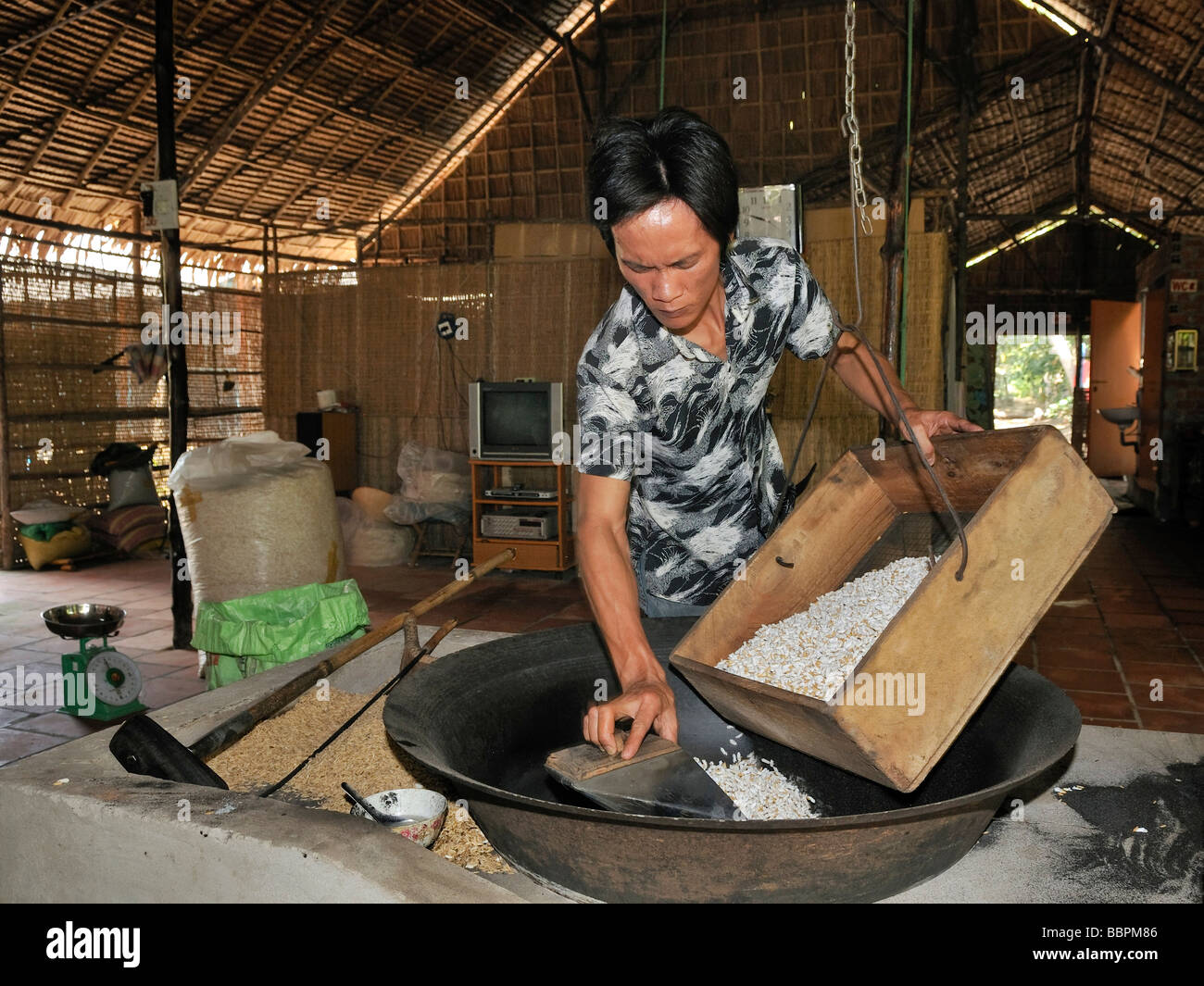 L'uomo la preparazione di riso soffiato, fabbrica dolciaria, Vinh Long, Delta del Mekong, Vietnam, sud-est asiatico Foto Stock