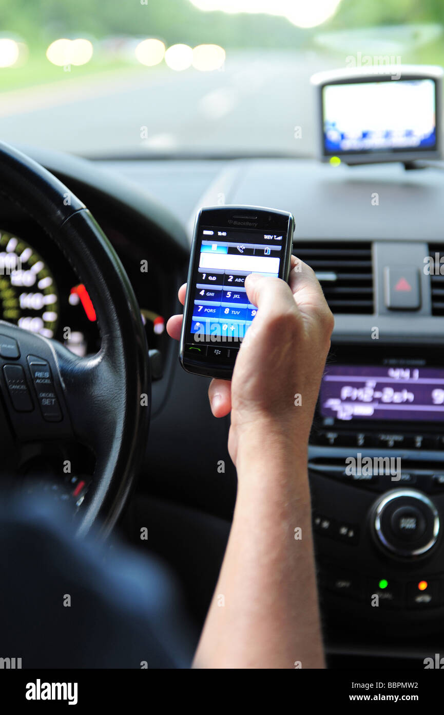 Uomo che utilizza un blackberry telefono cellulare per effettuare un calll mentre guidare la sua auto Foto Stock