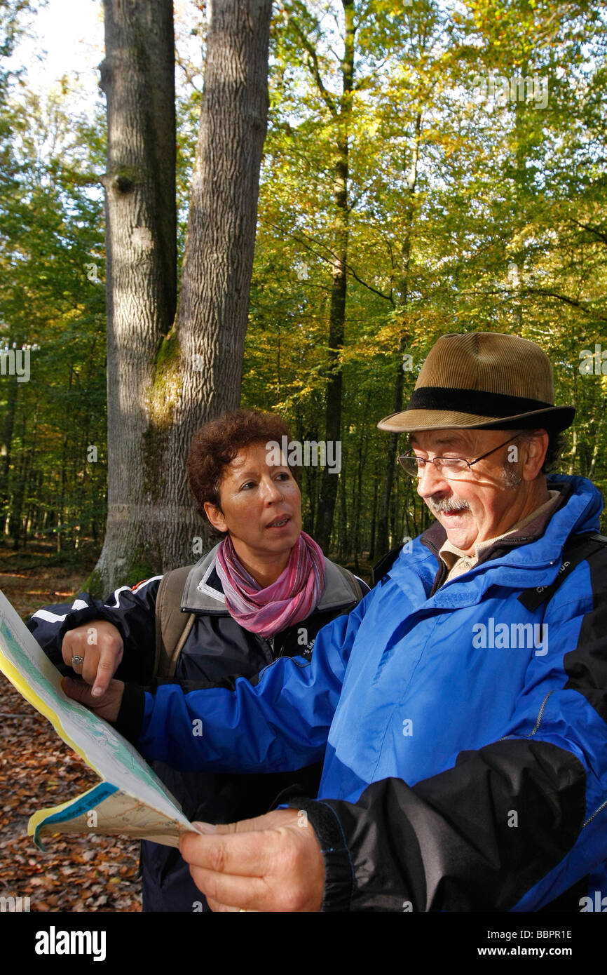 Una coppia di anziani con una mappa topografica per una passeggiata nella foresta di SENONCHES, EURE-ET-LOIR (28), Francia Foto Stock