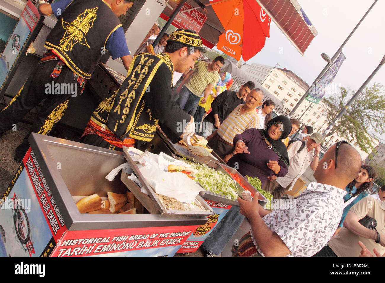 Istanbul Turchia donna turca che acquistando un pesce fritto a sandwich come noto un Balik Ekmek da un venditore ambulante a Eminonu Foto Stock