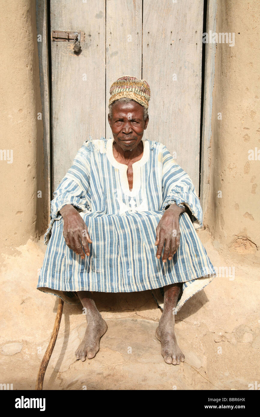 Un vecchio capo cieco si siede di fronte a casa sua in un villaggio nel nord del Ghana, Africa occidentale Foto Stock