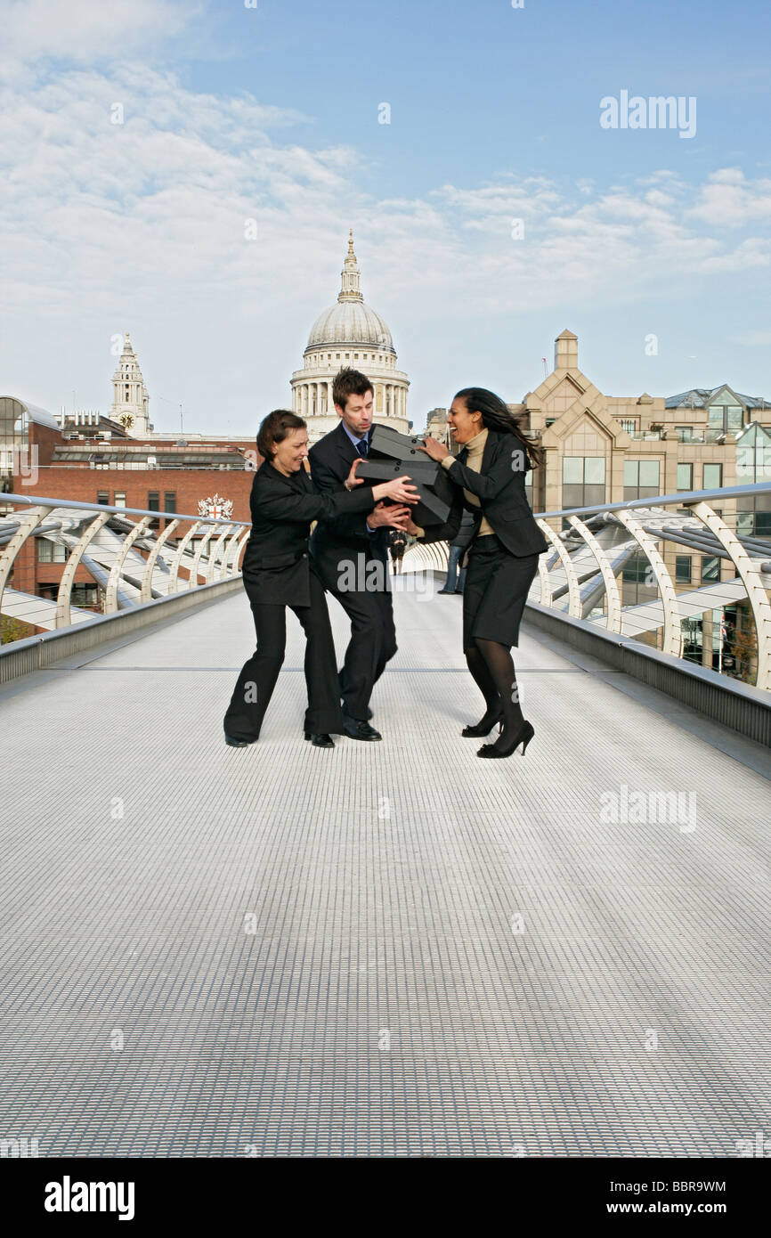 Tre persone di affari (due femmina, un maschio) sul millennio lottando per contenere una pila di scatole di file, Foto Stock