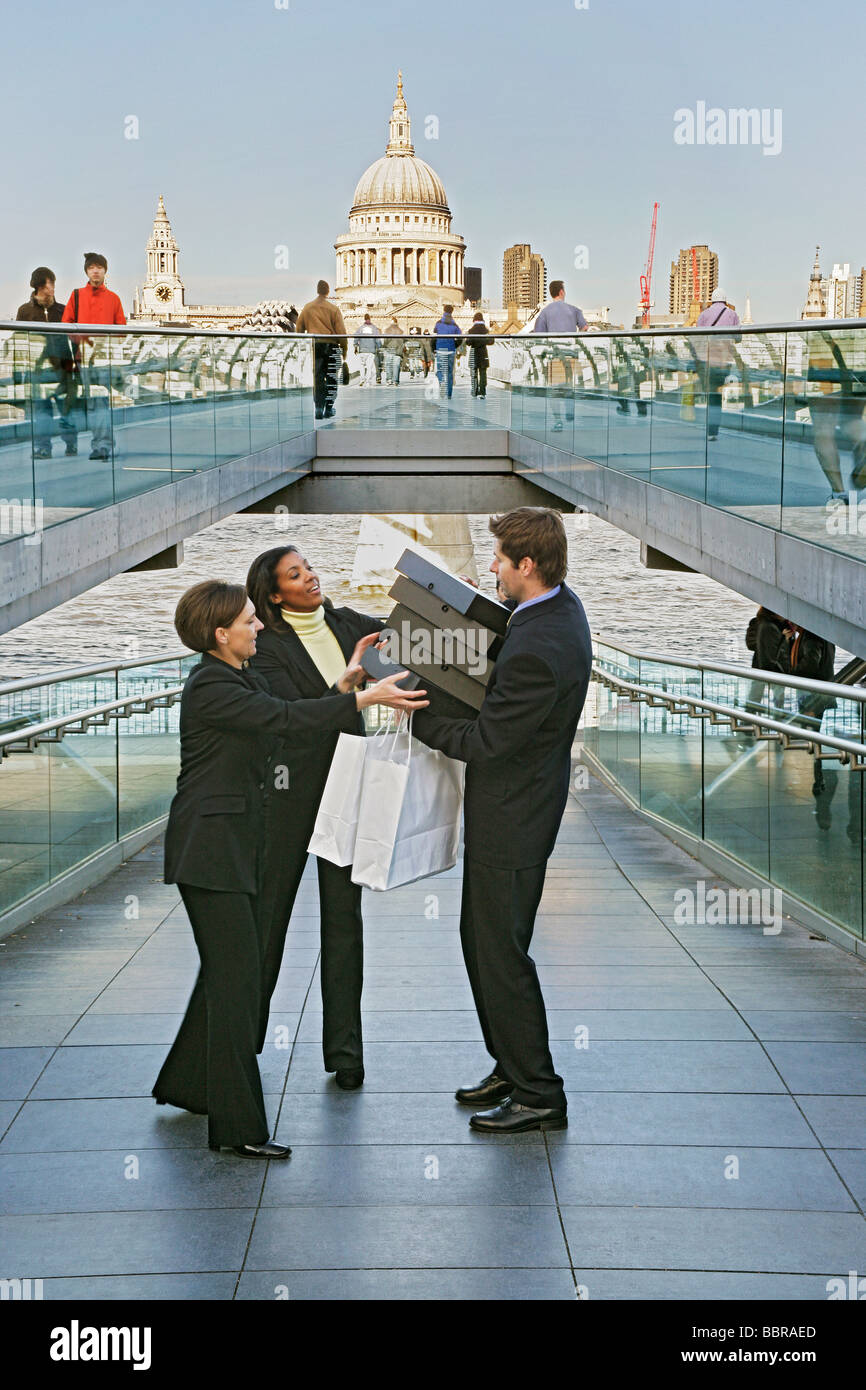 Tre persone di affari (due femmina, un maschio) sul millennio lottando per contenere una pila di scatole di file, Foto Stock