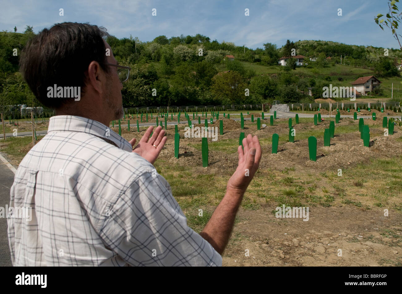 Un musulmano Bosniak uomo offrendo namaz rituale di preghiera in un cimitero di massa per il 1995 le vittime della guerra nel villaggio di Bratunac nella Repubblica Srpska in Bosnia Foto Stock