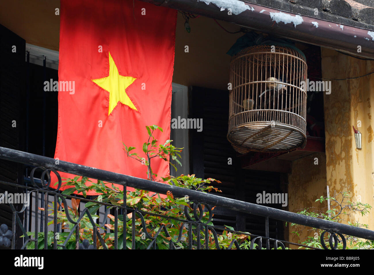 Nazionale vietnamita bandiera rossa e la birdcage sospesi dal balcone della casa, "Hoi An', Vietnam Foto Stock