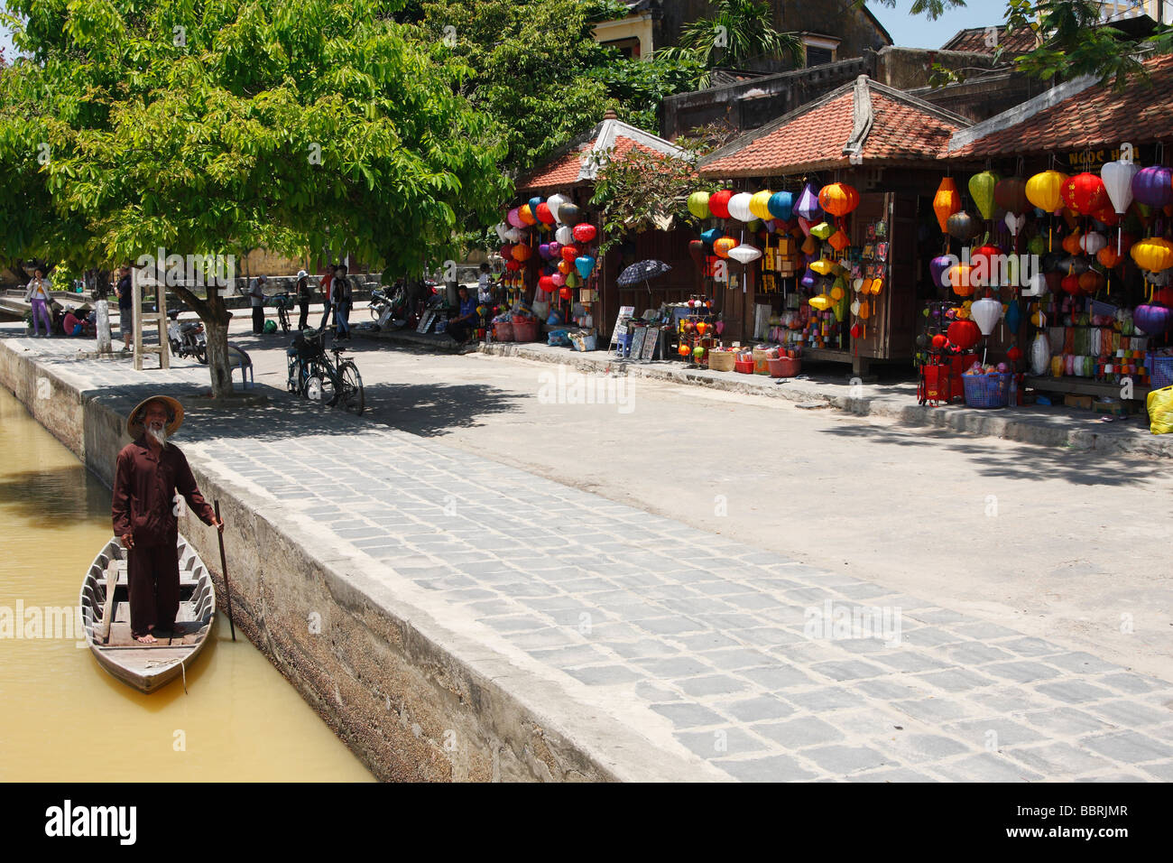 Il vecchio uomo vietnamita in piedi in barca accanto alla lanterna di colorate bancarelle, 'Hoi An', Vietnam Foto Stock