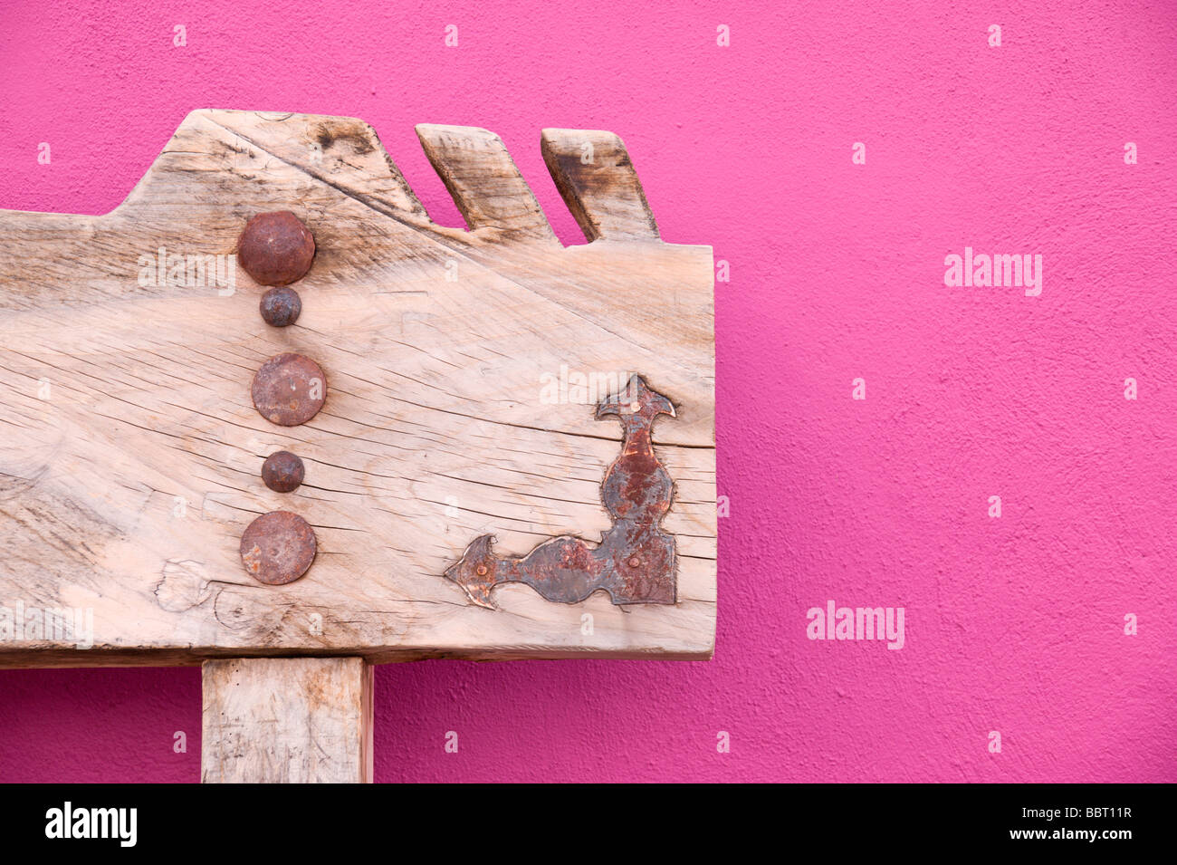 Decorate una panca di legno si appoggia contro una luminosa parete malva in Carrizozo, Nuovo Messico. Foto Stock