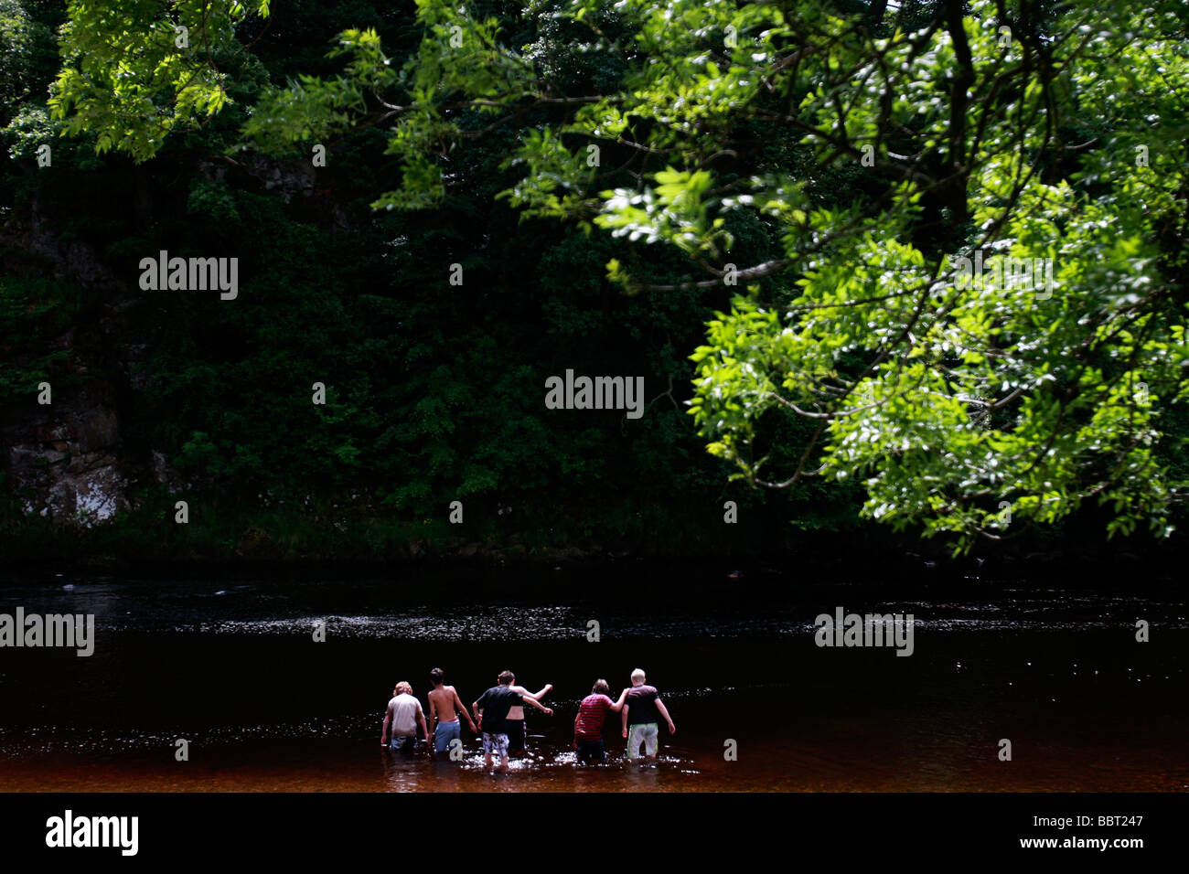 Bambini wade in un fiume di estate nonostante i pericoli entro Foto Stock