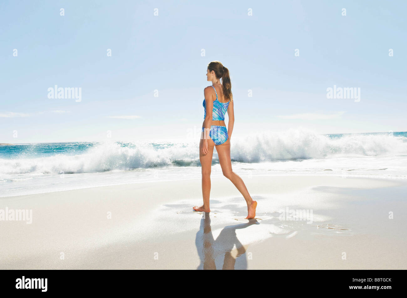 Una ragazza camminare lungo la spiaggia Foto Stock