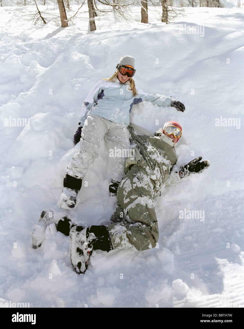 Giovane seduto nella neve, ridendo Foto Stock