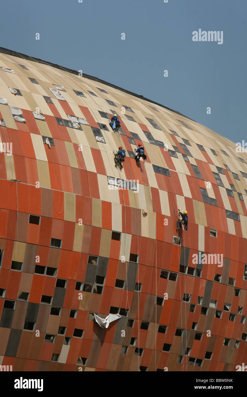 Lavoratori edili utilizzando corde per lavorare sulla parte esterna del Soccer City football Stadium che ospiterà la Coppa del Mondo di calcio Foto Stock