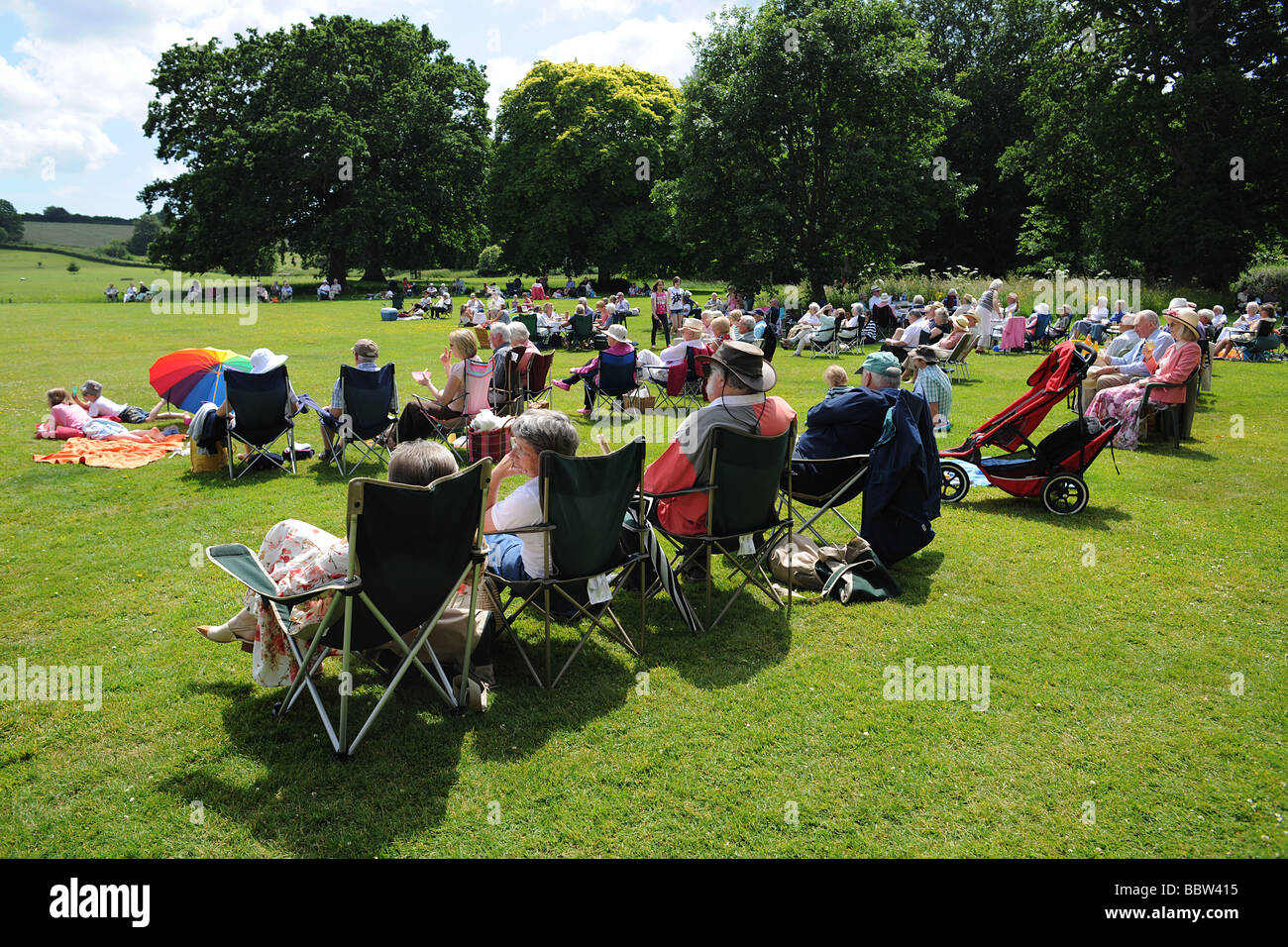 Folla di pubblico con picnic su un prato Ovest Paese Inghilterra in estate il sole Foto Stock