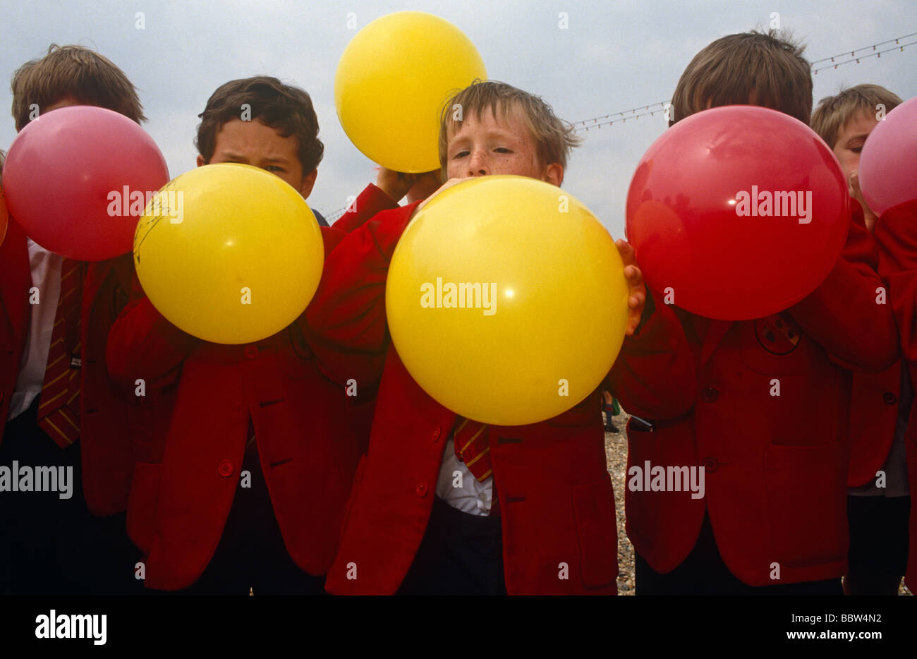 Blazored scolari gonfiare il rosso e il giallo palloncini in un gioco in spiaggia durante una giornata di mare-viaggio a Brighton Foto Stock