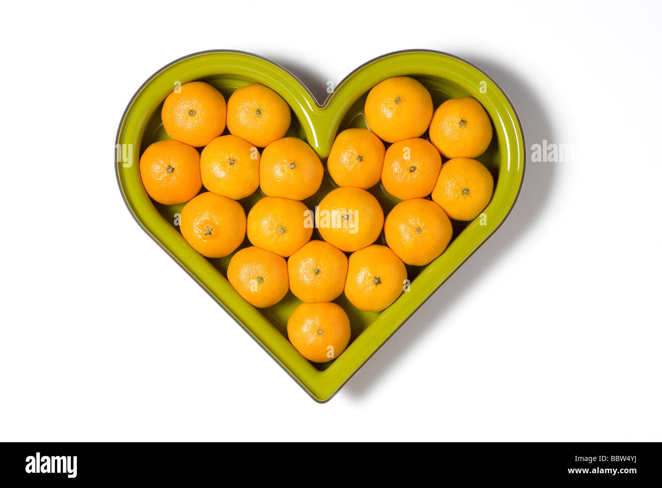 Cuore verde a forma di coppa di frutta piena di arance Foto Stock