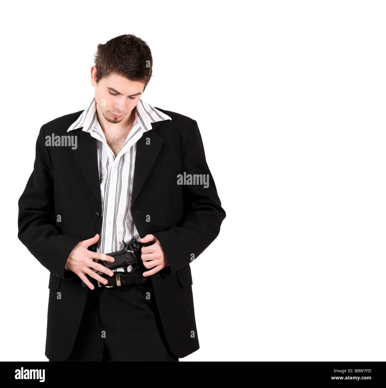 Ritratto di giovane maschio del bodyguard guardando a pistola in pantaloni, studio shot Foto Stock