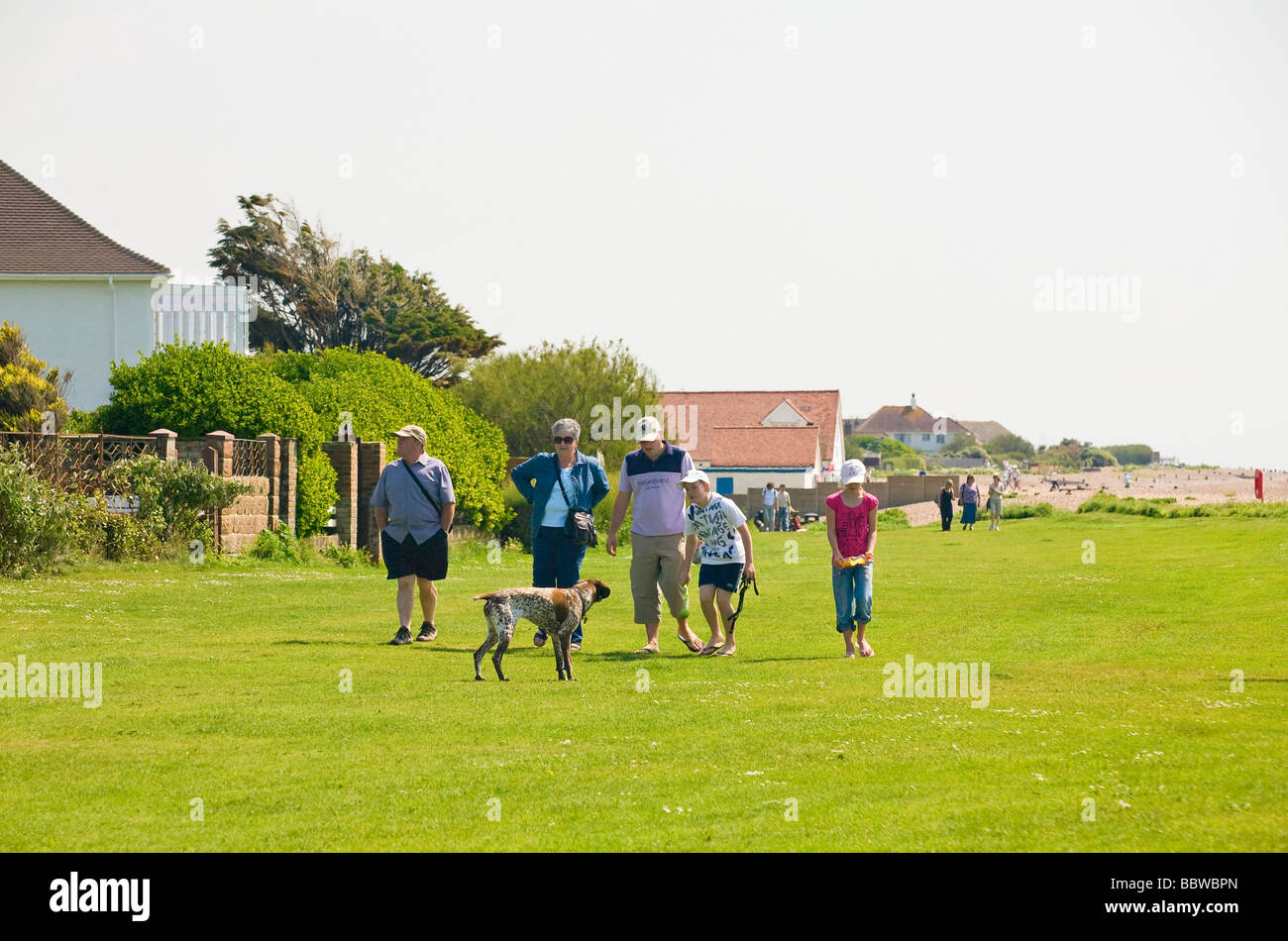 Una famiglia a spasso il loro cane lungo la greensward presso la Ferring Beach, West Sussex, in Inghilterra, Regno Unito Foto Stock