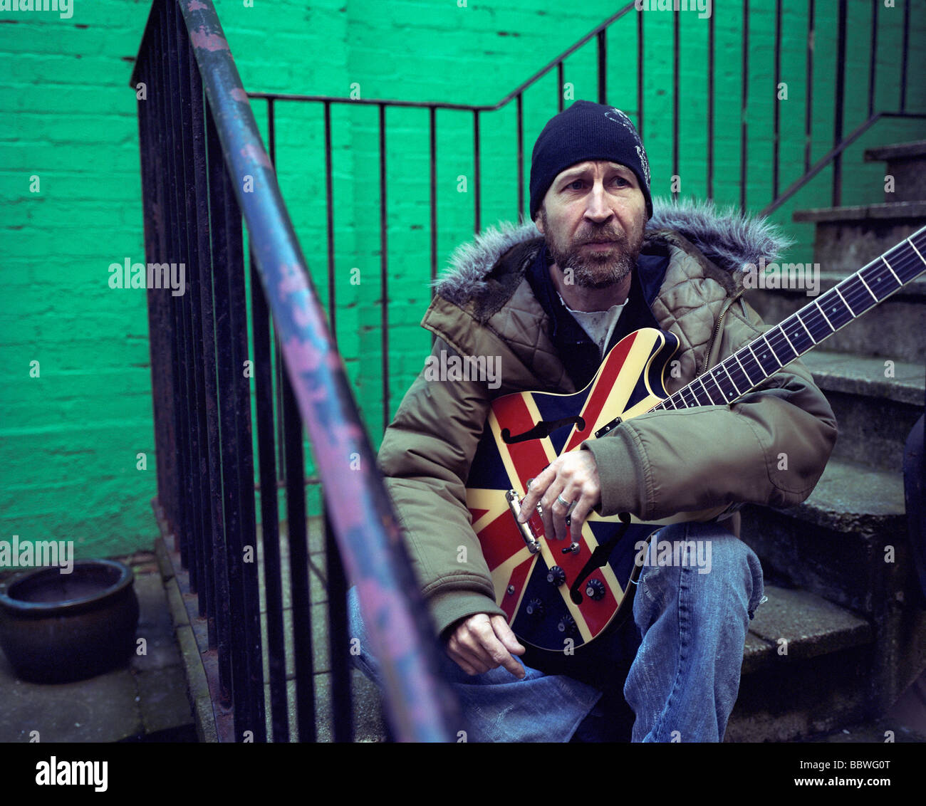 Esercito britannico veterano siede sui gradini con pregiato possesso chitarra elettrica in aiuto dei veterani senzatetto mens' shelter Foto Stock