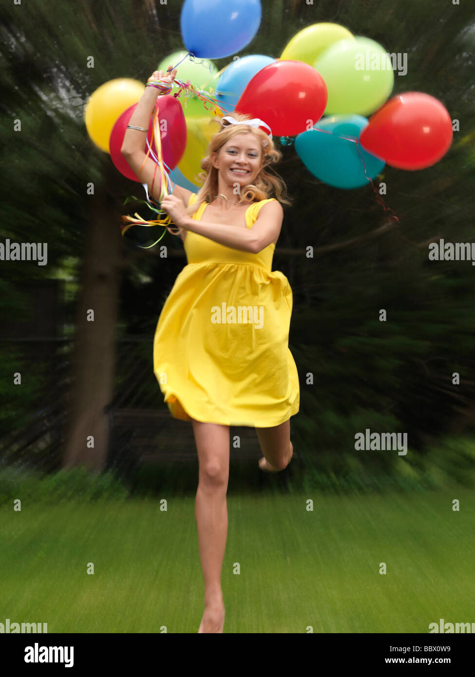 Giovane donna felice in esecuzione con un mazzetto di colorati palloncini di aria Foto Stock