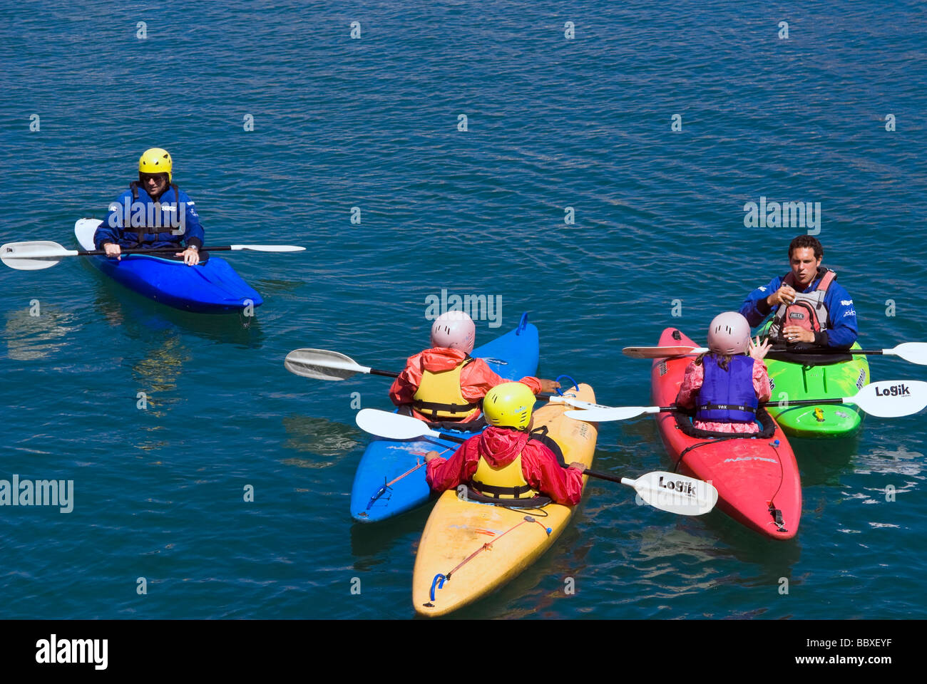Due istruttori e tre bambini canoa in mare in un porto. Colori del mare kayak. Canoe con ragazzi e ragazze che hanno una lezione. Foto Stock