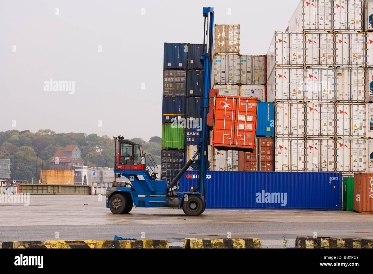 Un contenitore carrello pile e carica i contenitori ISO in un porto. Foto Stock