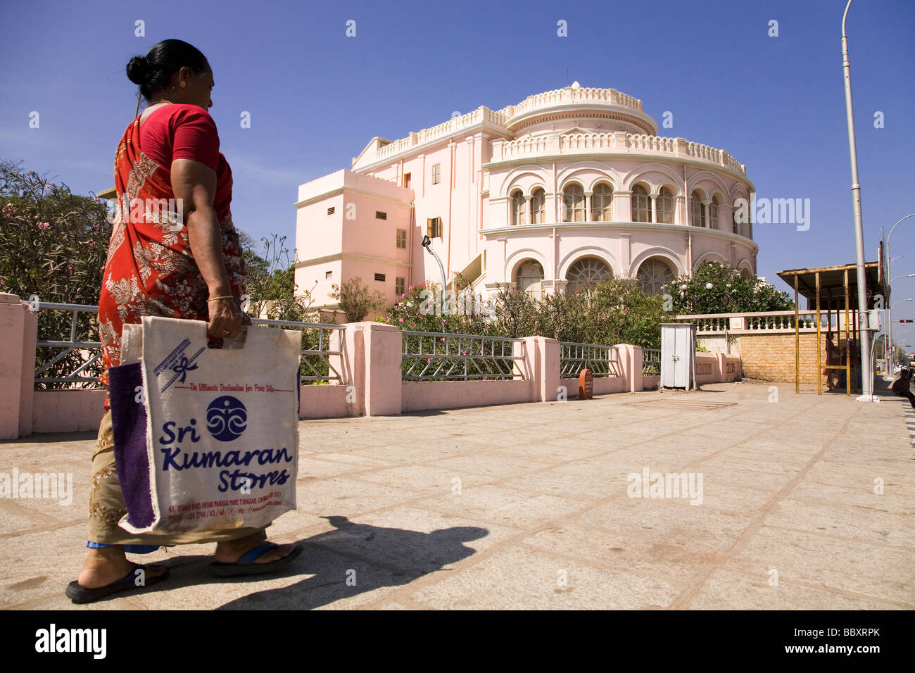 Una donna indiana in un sari passeggiate lungo il marciapiede esterno del Ramakrishna Mission (Ice House) a Chennai, India. Foto Stock