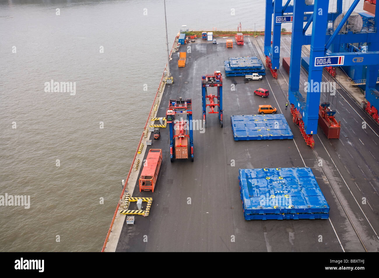 Guardando verso il basso su un "straddle carrier carrello in movimento i contenitori ISO da terminali portuali ulteriormente nel terminal per container. Foto Stock