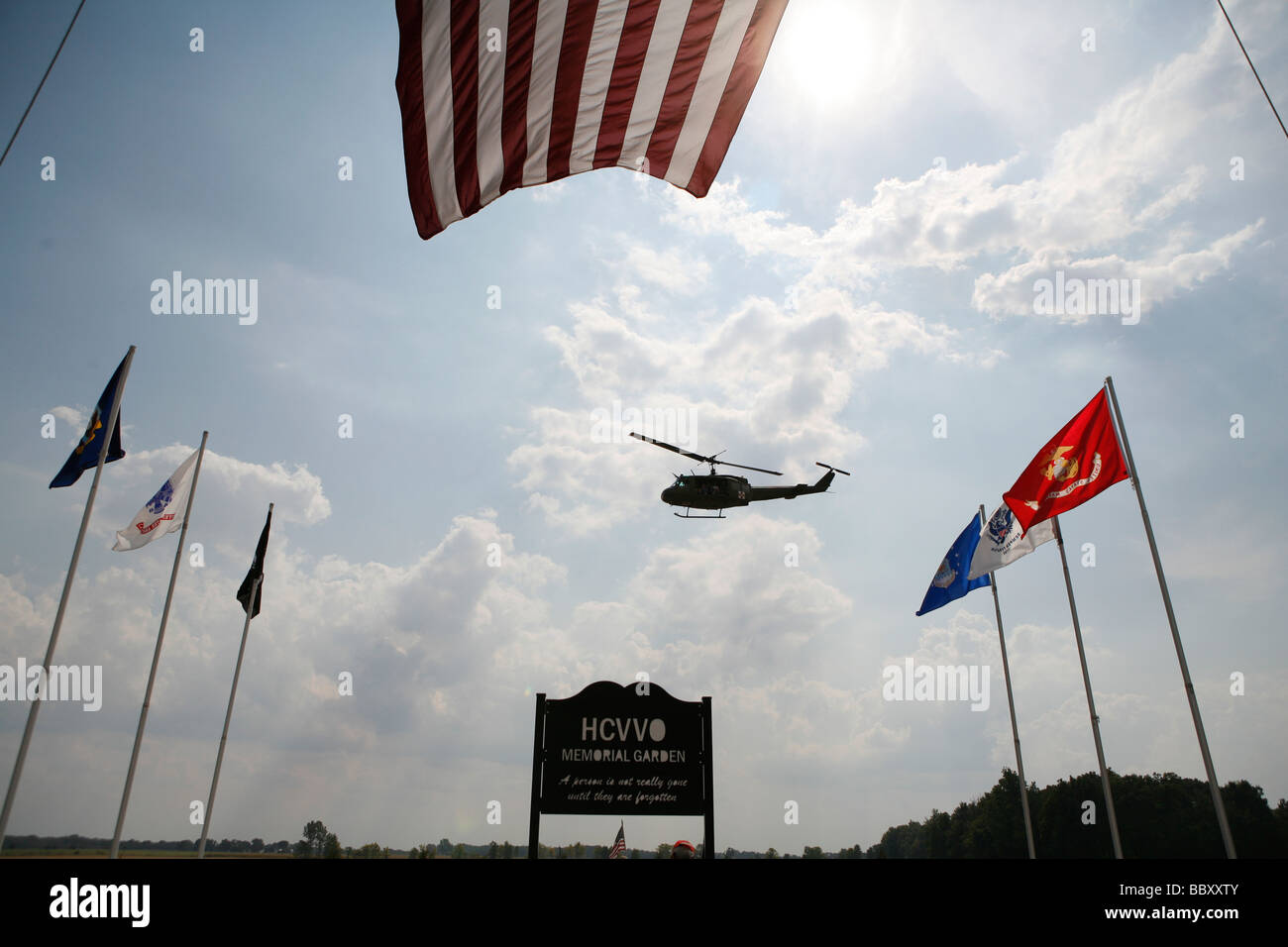 Un Vietnam era Huey restaurato da American Huey 369 vola in passato una grande bandiera americana. Foto Stock