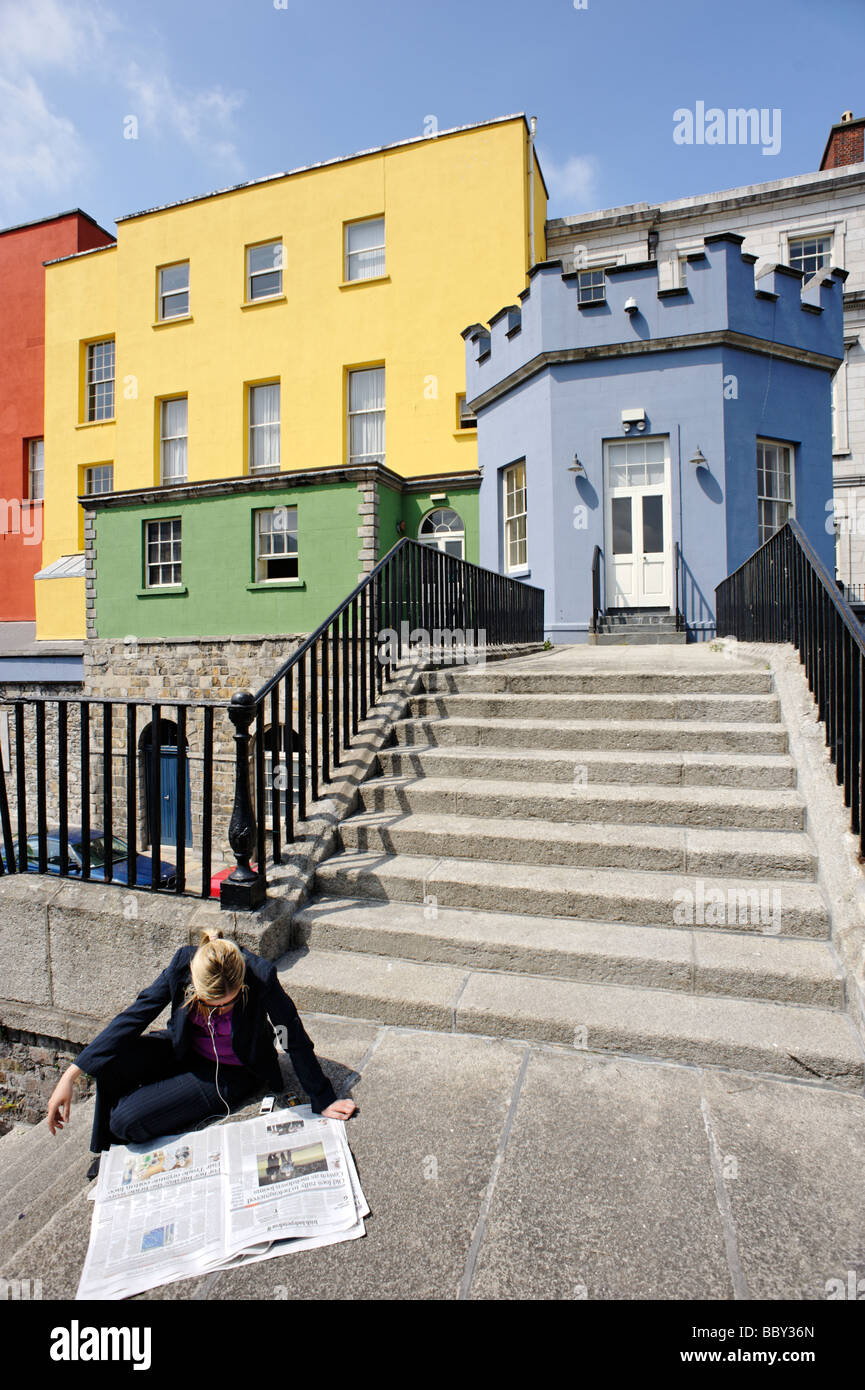 Persona la lettura di un quotidiano nella parte anteriore del dipinto in maniera colorata edifici esterni del Castello di Dublino Dublino Repubblica di Irlanda Foto Stock