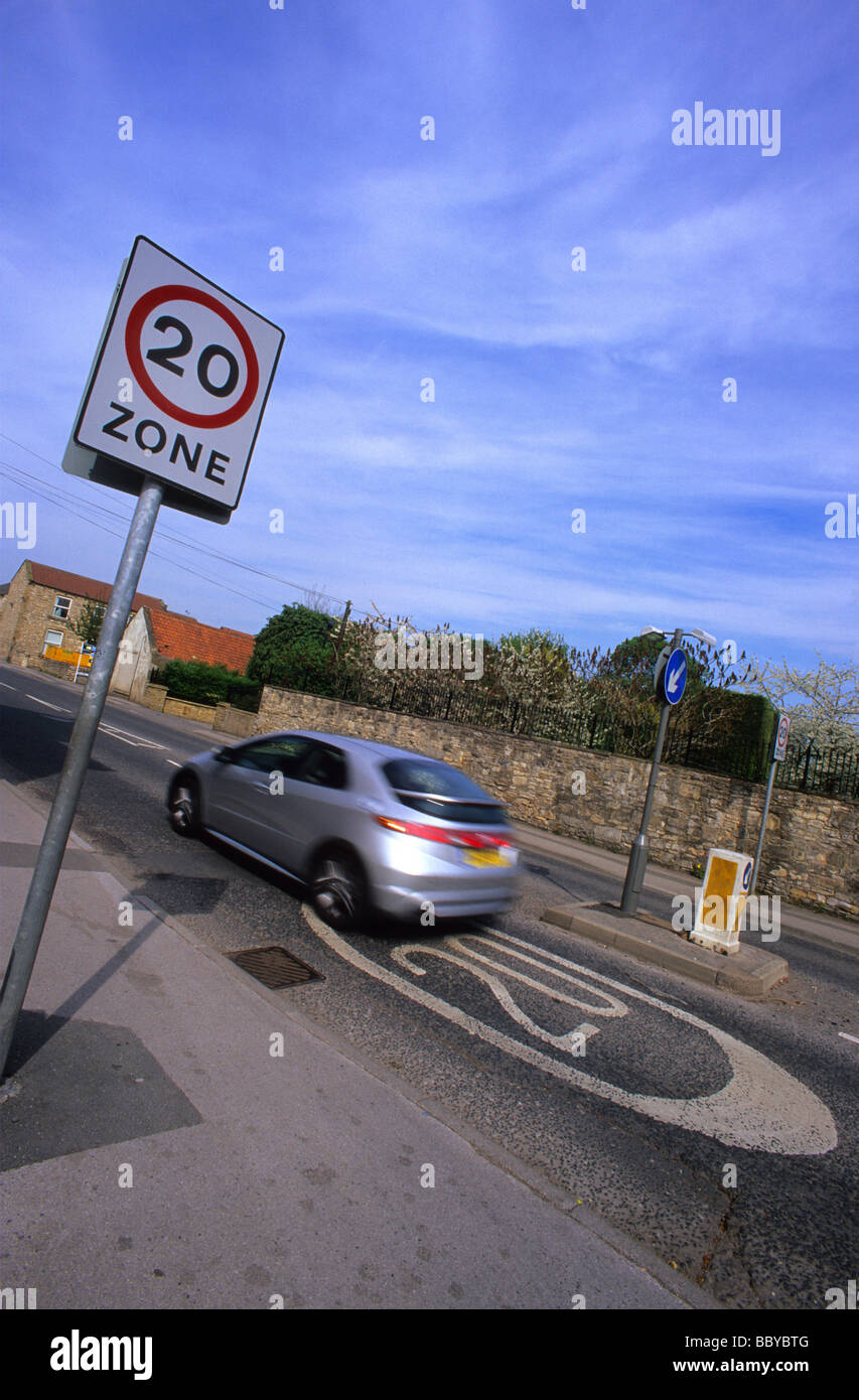 Auto passando a 20 miglia per ora il limite massimo di velocità zona segno di avvertimento sulla strada attraverso il villaggio nei pressi di Leeds Yorkshire Regno Unito Foto Stock