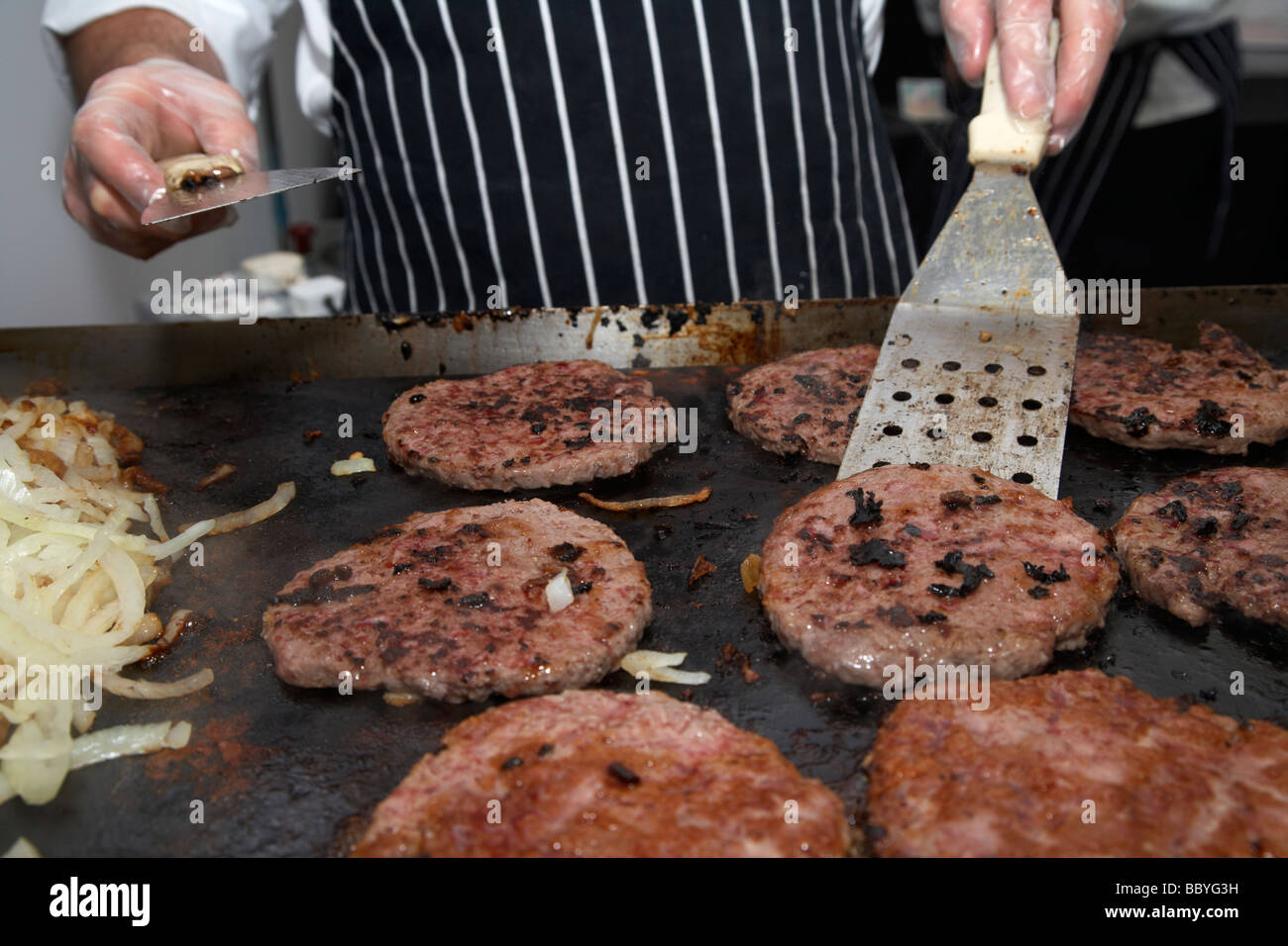 La cucina dello chef hamburger su un grill aperto, piastra riscaldante per la vendita in un evento pubblico contea di Down Irlanda del Nord Regno Unito Foto Stock