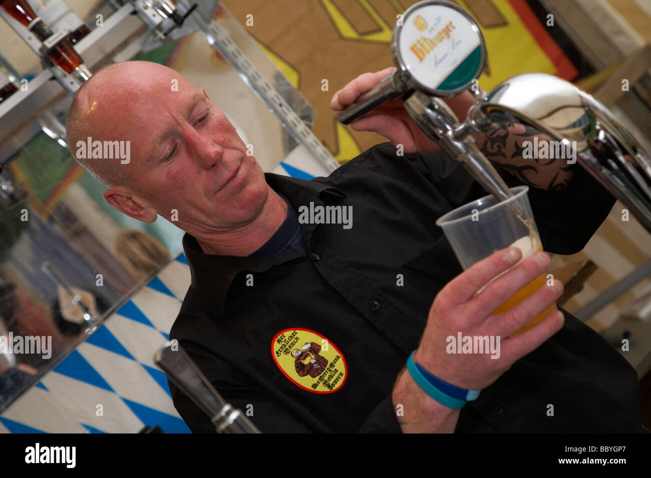 Barman una colata di birra in una tazza di plastica in una imitazione tedesco di stallo di birra nel Regno Unito Foto Stock