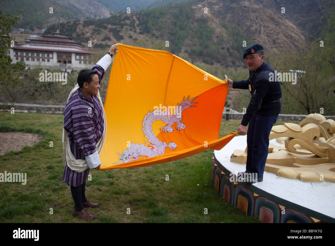 Soldato bhutanesi guard ripiegamento Bhutan bandiera nazionale al palazzo del re, Thimphu. Visualizzazione orizzontale Foto Stock