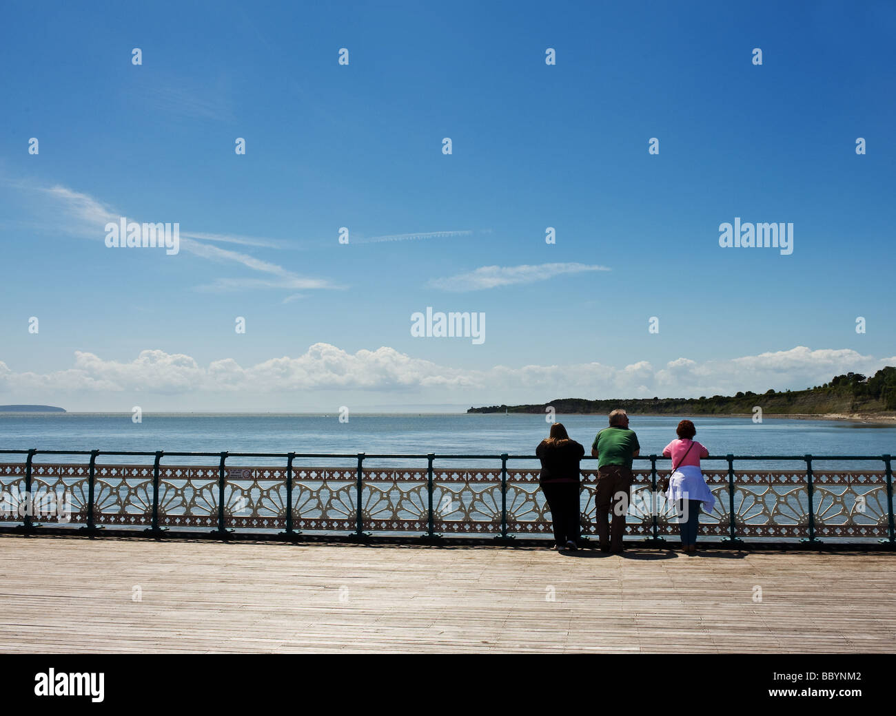 Tre persone appoggiata sulla ringhiera sul Penarth Pier nel Galles del Sud. Foto di Gordon Scammell Foto Stock