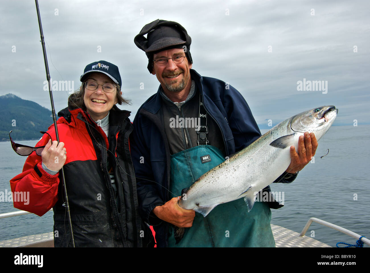 Pescatore femmina indossando resort berretto da baseball con guida di pesca tenendo un appena sbarcati Salmone Chinook pronti per il rilascio Foto Stock