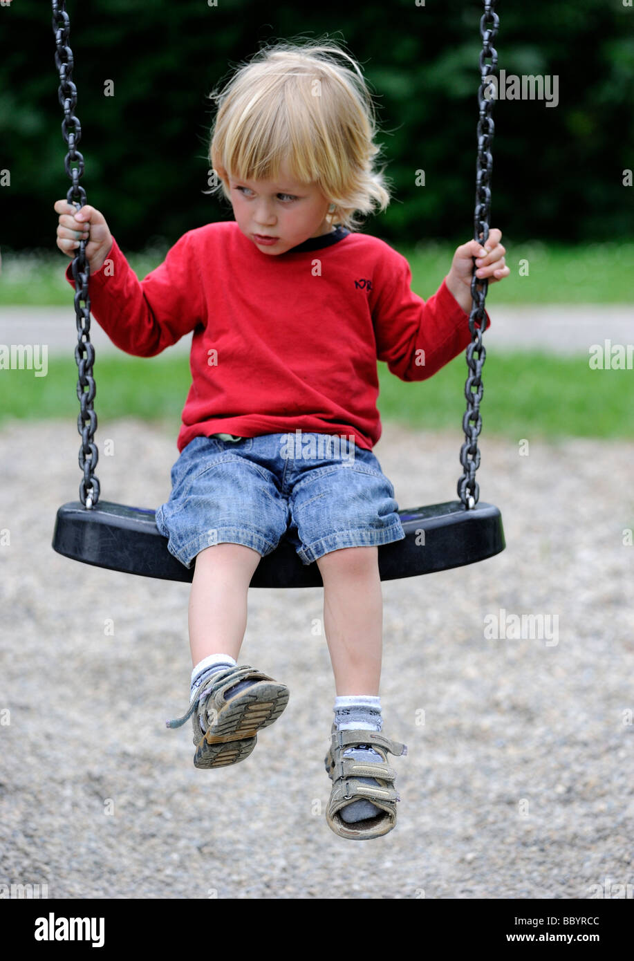 Bambino ragazzo biondo sull'altalena / altalena da solo Foto Stock