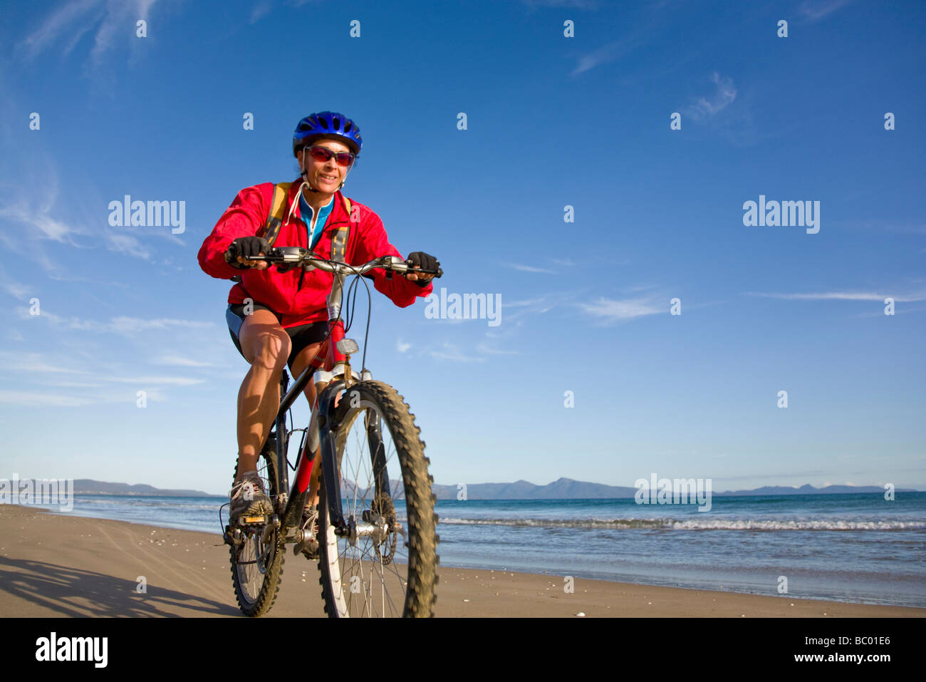 Una donna godendo di un giro in bici su nove miglia di spiaggia sulla costa est della Tasmania, Australia. Foto Stock